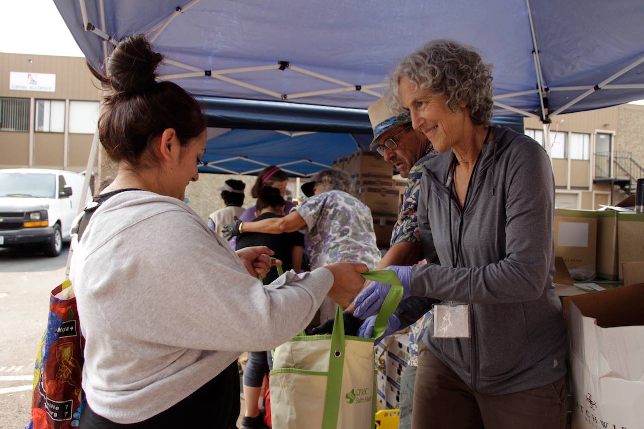 Older woman volunteer filling bag of young woman