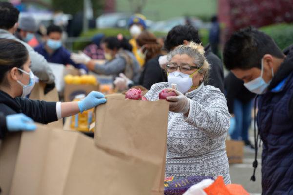 Volunteer Anita Hernandez of San Rafael and others prepare bags of food to give away during a community food distribution event