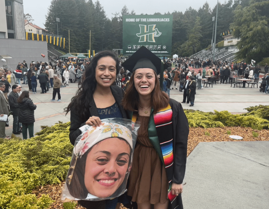 Claudia Garcia holds up a blown up cut out of Maria Espinosa and Maria Espinosa pose for Maria's graduation photo.